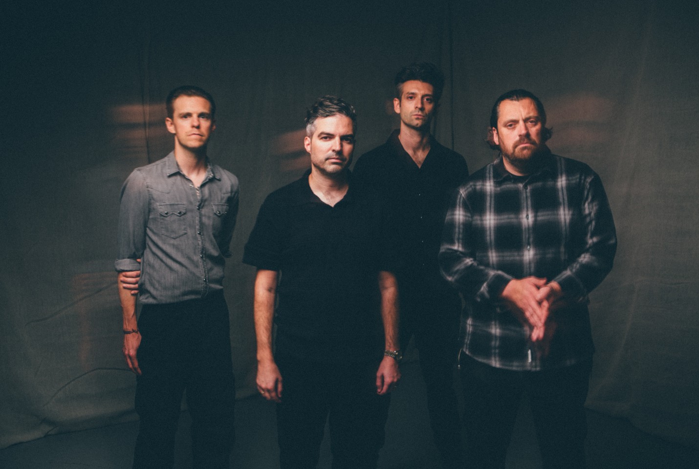 4 men (the boxer rebellion) standing in front of a dark sheet 
